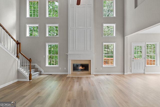 1429 Kentmire Ct, Locust Grove, GA 30248 - unfurnished living room featuring a high ceiling, stairway, a fireplace, light wood finished floors, and baseboards