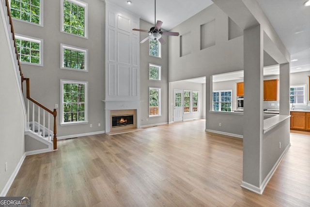 1429 Kentmire Ct, Locust Grove, GA 30248 - unfurnished living room featuring light wood-style flooring, stairs, baseboards, plenty of natural light, and a high ceiling