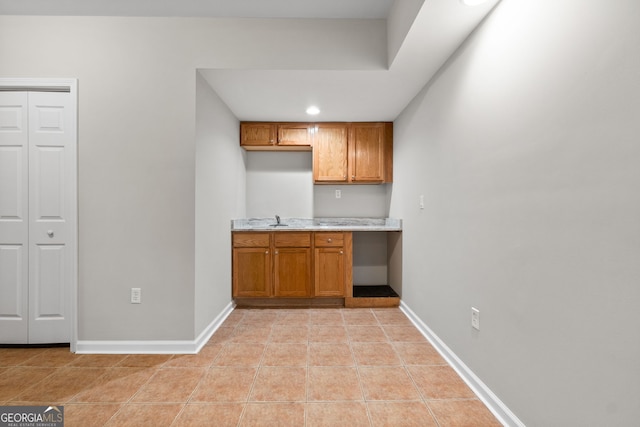 1429 Kentmire Ct, Locust Grove, GA 30248 - kitchen featuring light countertops, brown cabinetry, a sink, baseboards, and recessed lighting