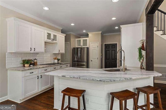 kitchen featuring stainless steel fridge, a sink, a kitchen breakfast bar, crown molding, and glass insert cabinets