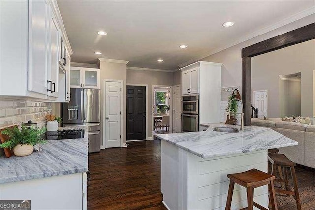 kitchen with a sink, stainless steel appliances, white cabinets, light stone countertops, and recessed lighting