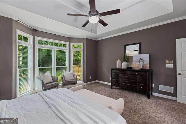 bedroom featuring baseboards, a tray ceiling, carpet floors, a ceiling fan, and ornamental molding