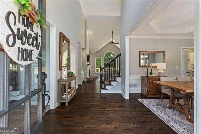 foyer featuring wood finished floors, stairway, crown molding, baseboards, and a chandelier
