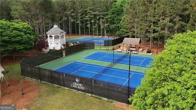 view of tennis court with a view of trees and fence