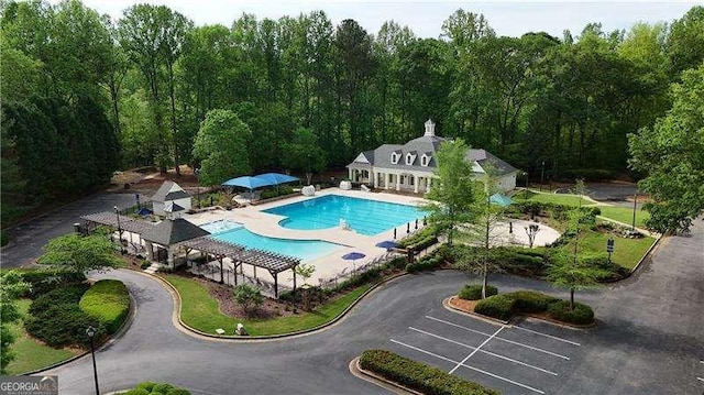 community pool with a patio area, an outbuilding, and a wooded view