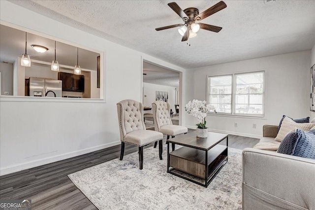 living area featuring wood finished floors, ceiling fan, a textured ceiling, and baseboards