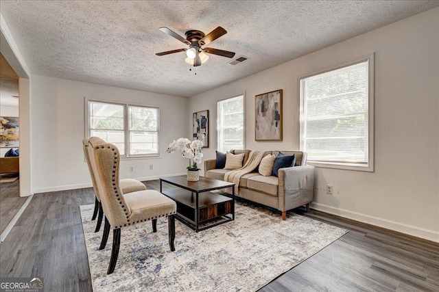 living area with a textured ceiling, ceiling fan, wood finished floors, and baseboards