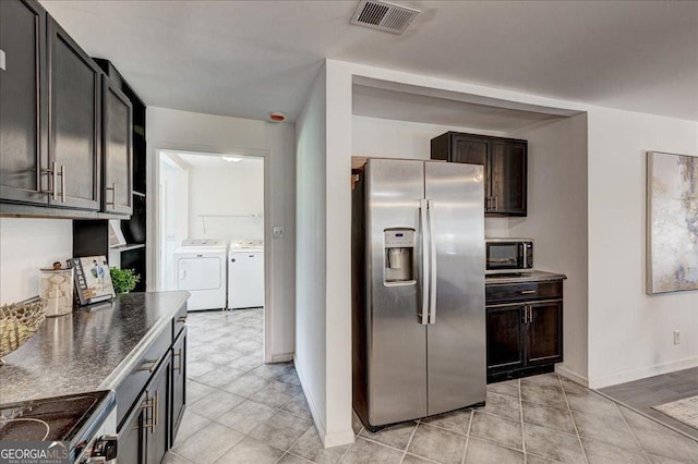 kitchen with stainless steel appliances, washer and dryer, baseboards, dark countertops, and dark brown cabinets