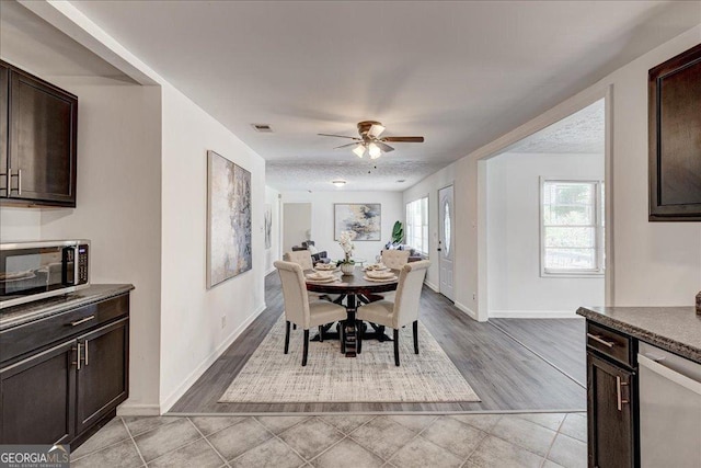 dining space featuring baseboards, a ceiling fan, and light wood-style floors