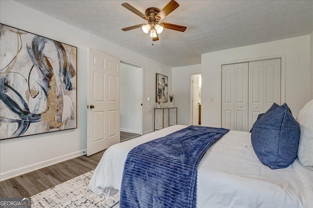 bedroom featuring wood finished floors, a textured ceiling, baseboards, a closet, and a ceiling fan