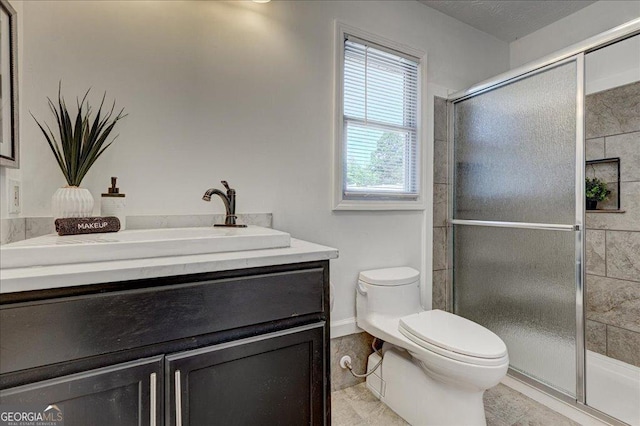 full bathroom featuring toilet, a stall shower, and vanity