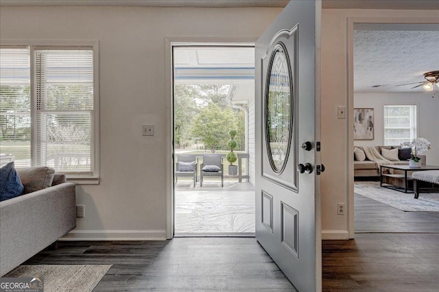 foyer with wood finished floors, ceiling fan, baseboards, and a textured ceiling