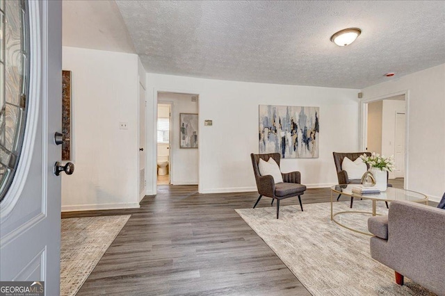foyer with a textured ceiling, wood finished floors, and baseboards