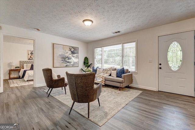 foyer with wood finished floors, baseboards, and a textured ceiling