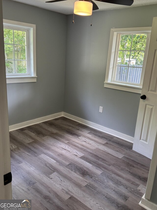 unfurnished room with ceiling fan, wood finished floors, and baseboards