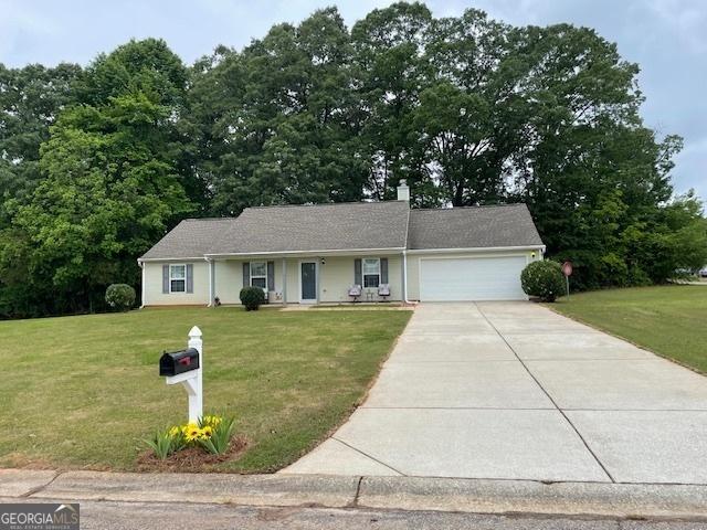 single story home with an attached garage, driveway, a front lawn, and a chimney