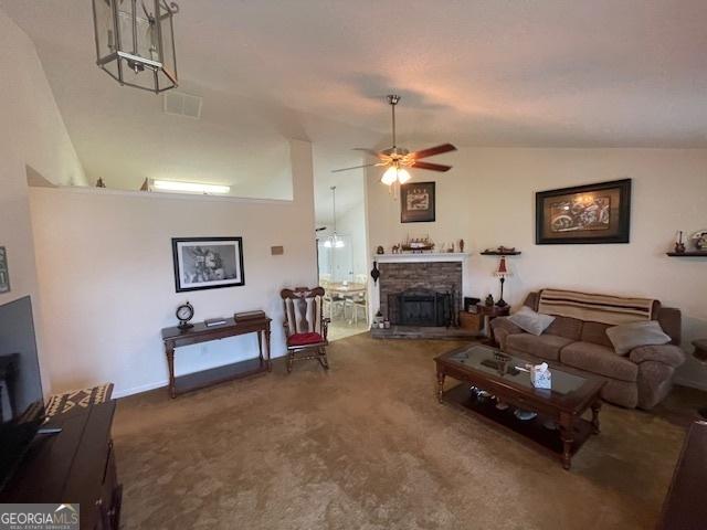 carpeted living room with lofted ceiling, ceiling fan, and a stone fireplace