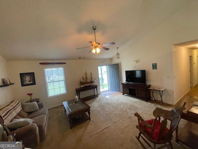 carpeted living room featuring vaulted ceiling, healthy amount of natural light, a ceiling fan, and baseboards