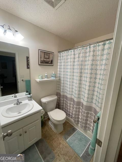 bathroom with a textured ceiling, vanity, toilet, and a shower with curtain