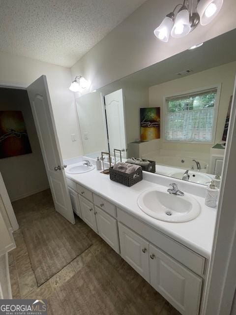 bathroom with double vanity, a textured ceiling, a chandelier, a tub, and wood finished floors