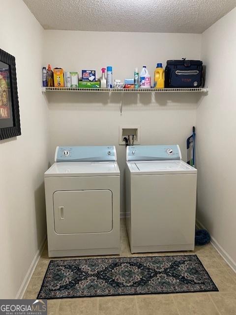 laundry room with independent washer and dryer, baseboards, a textured ceiling, and light tile patterned floors