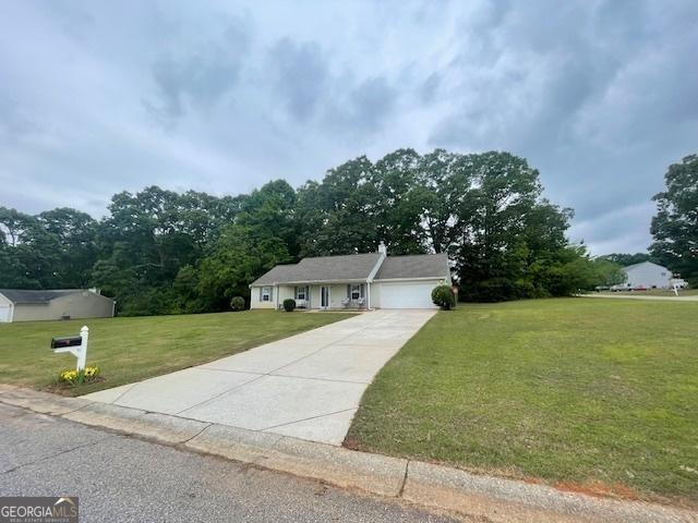 view of front facade with a front yard, a garage, and concrete driveway