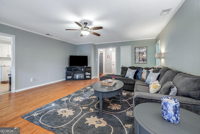 living area featuring wood finished floors, a ceiling fan, crown molding, and baseboards