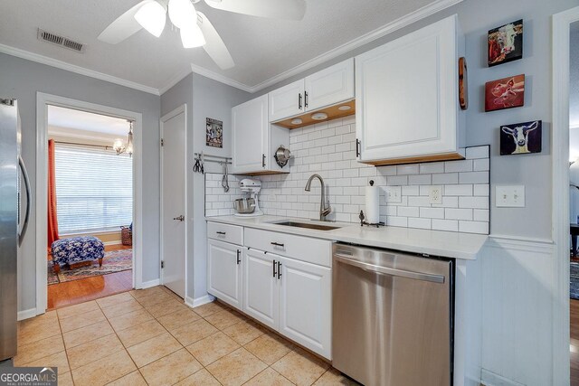 kitchen featuring appliances with stainless steel finishes, a sink, light countertops, tasteful backsplash, and crown molding