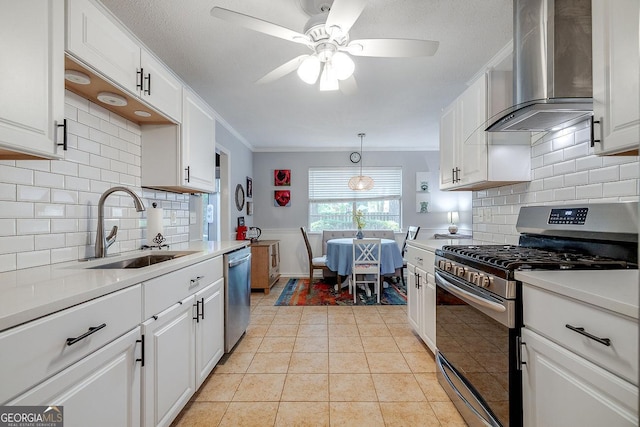 kitchen with stainless steel appliances, wall chimney exhaust hood, a sink, white cabinets, and light countertops