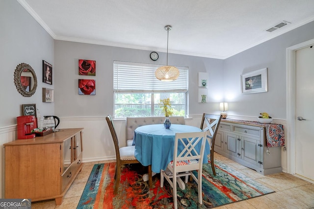 dining space with ornamental molding and a wainscoted wall