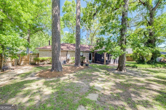 view of yard with a sunroom, fence, and a gate
