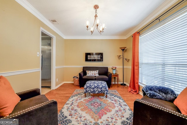 living room with a chandelier, ornamental molding, healthy amount of natural light, wood finished floors, and baseboards