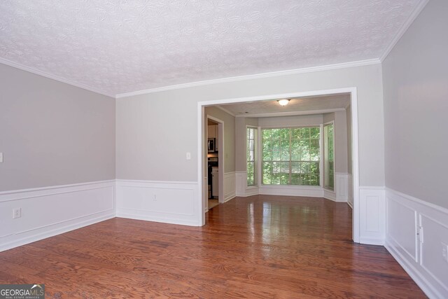 1076 Plantation Blvd SE, Conyers, GA 30094 - empty room featuring wood finished floors, a textured ceiling, wainscoting, and crown molding