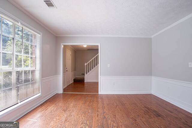 1076 Plantation Blvd SE, Conyers, GA 30094 - empty room featuring wood finished floors, a textured ceiling, a wainscoted wall, and ornamental molding