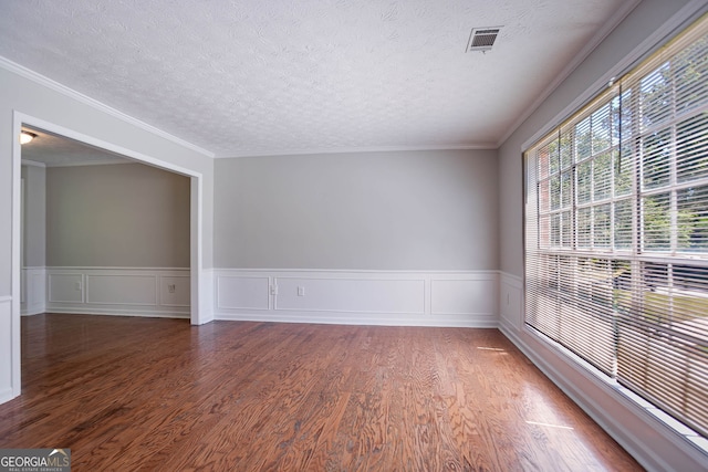1076 Plantation Blvd SE, Conyers, GA 30094 - spare room featuring wood finished floors, a textured ceiling, a wainscoted wall, and crown molding