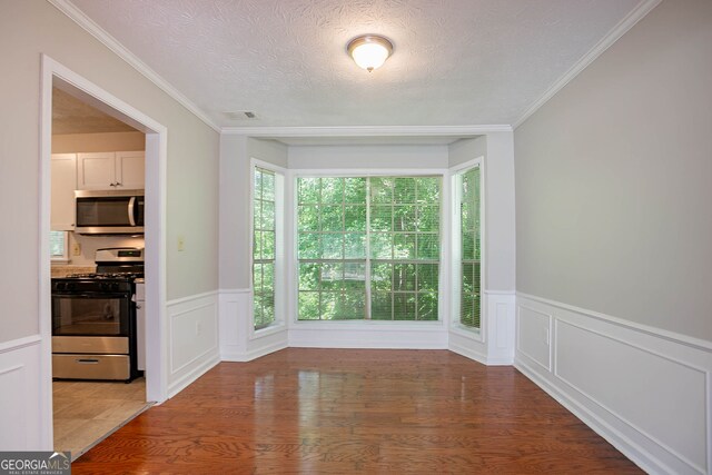 1076 Plantation Blvd SE, Conyers, GA 30094 - unfurnished room with a textured ceiling, wood finished floors, wainscoting, and a decorative wall