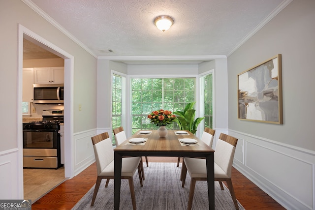 1076 Plantation Blvd SE, Conyers, GA 30094 - dining space featuring a decorative wall, a wainscoted wall, a textured ceiling, crown molding, and wood finished floors