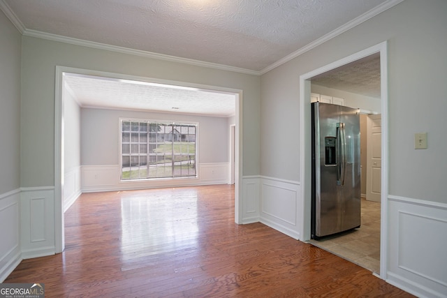 1076 Plantation Blvd SE, Conyers, GA 30094 - empty room featuring light wood finished floors, a wainscoted wall, a textured ceiling, a decorative wall, and ornamental molding