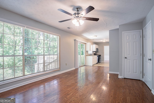 1076 Plantation Blvd SE, Conyers, GA 30094 - unfurnished living room featuring a textured ceiling, a ceiling fan, and wood finished floors