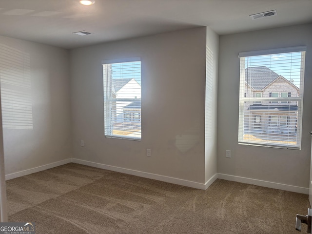 empty room featuring light colored carpet, plenty of natural light, and baseboards