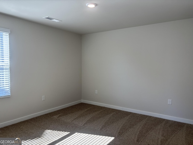 unfurnished room with dark carpet and baseboards