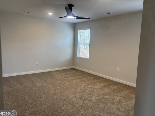 spare room featuring ceiling fan, dark carpet, and baseboards