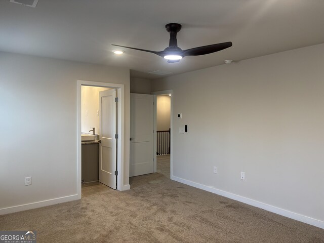 unfurnished bedroom with light colored carpet, baseboards, connected bathroom, and ceiling fan