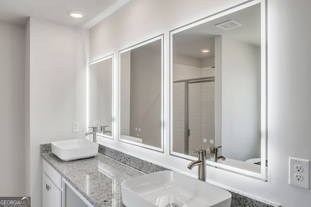 bathroom featuring a shower stall, double vanity, and recessed lighting