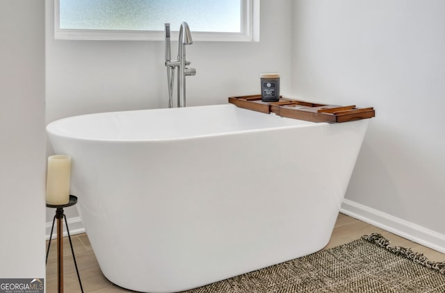 bathroom view of a freestanding tub, a sink, and baseboards
