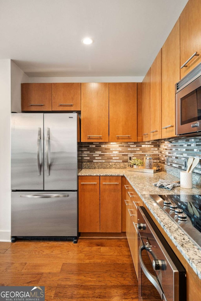 20 10th St NW Unit 2003, Atlanta, GA 30309 - kitchen with stainless steel appliances, light stone counters, light wood-style floors, decorative backsplash, and recessed lighting