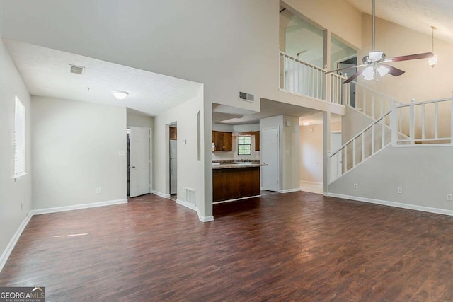 1074 Cherokee Hts, Stone Mountain, GA 30083 - unfurnished living room with dark wood-style floors, ceiling fan, stairway, and high vaulted ceiling