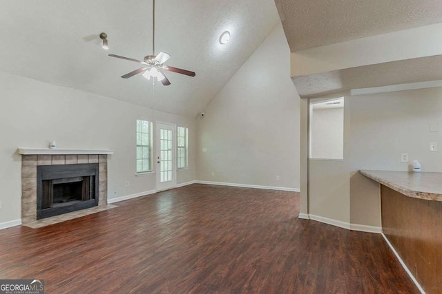 1074 Cherokee Hts, Stone Mountain, GA 30083 - unfurnished living room with a ceiling fan, wood finished floors, a tile fireplace, a textured ceiling, and high vaulted ceiling