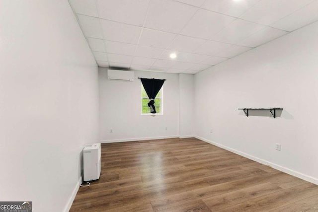 418 Whisper Wood Way, Locust Grove, GA 30248 - unfurnished room featuring a wall mounted AC, wood finished floors, baseboards, and a paneled ceiling
