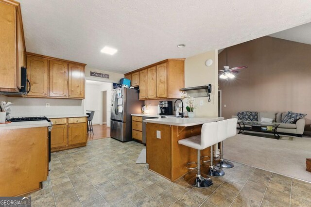 418 Whisper Wood Way, Locust Grove, GA 30248 - kitchen featuring stainless steel appliances, a peninsula, a sink, and brown cabinetry